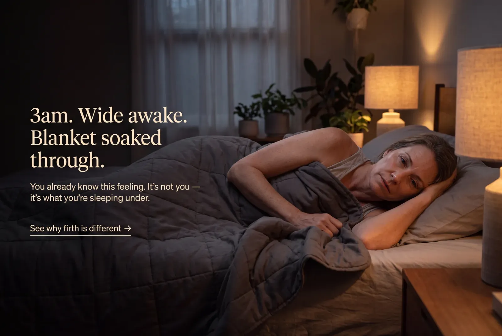 Woman lying awake at 3am under a heavy blanket in warm bedroom light